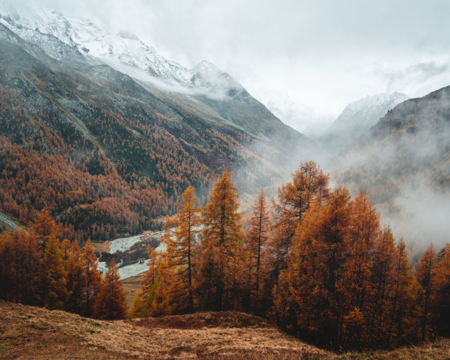 mountains are covered with snow while the fog is highing up